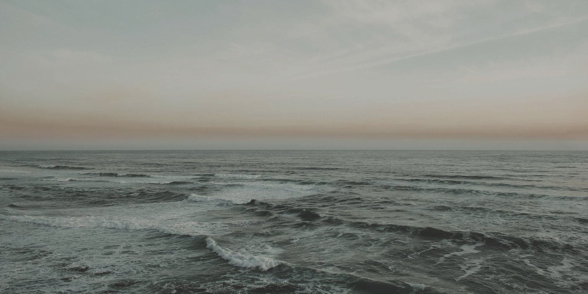 A muted band of sea meeting an overcast sky.