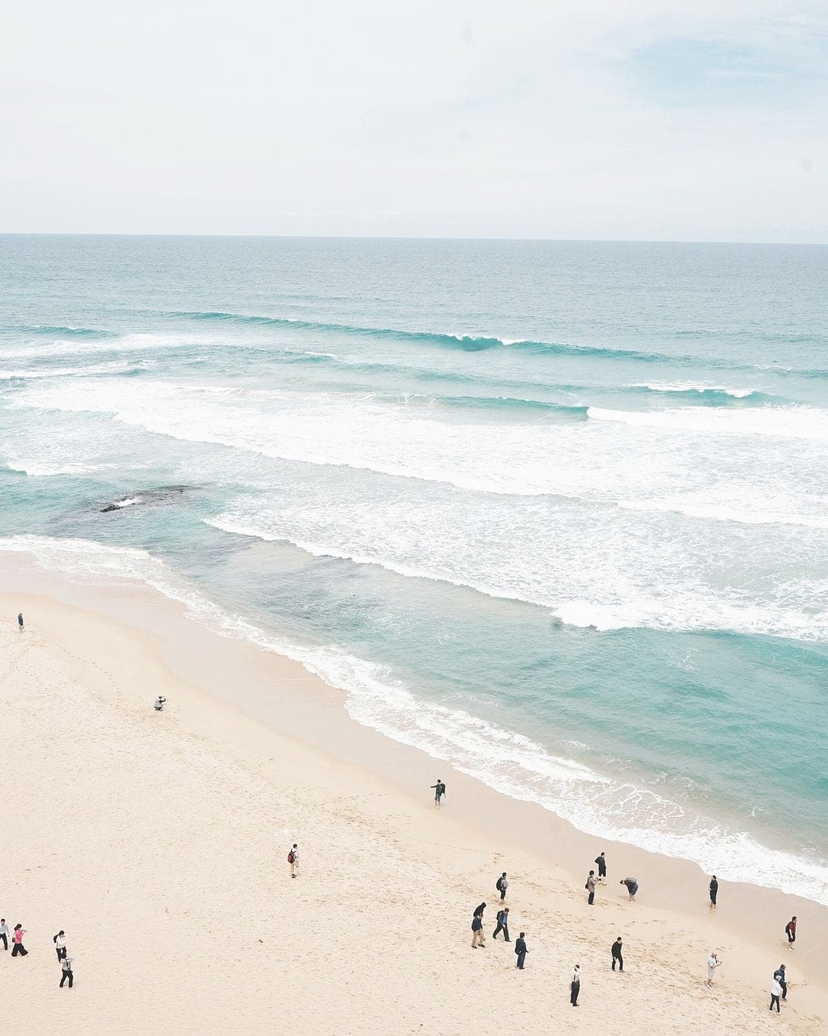 A wide Pacific beach with long lines of surf under soft light.