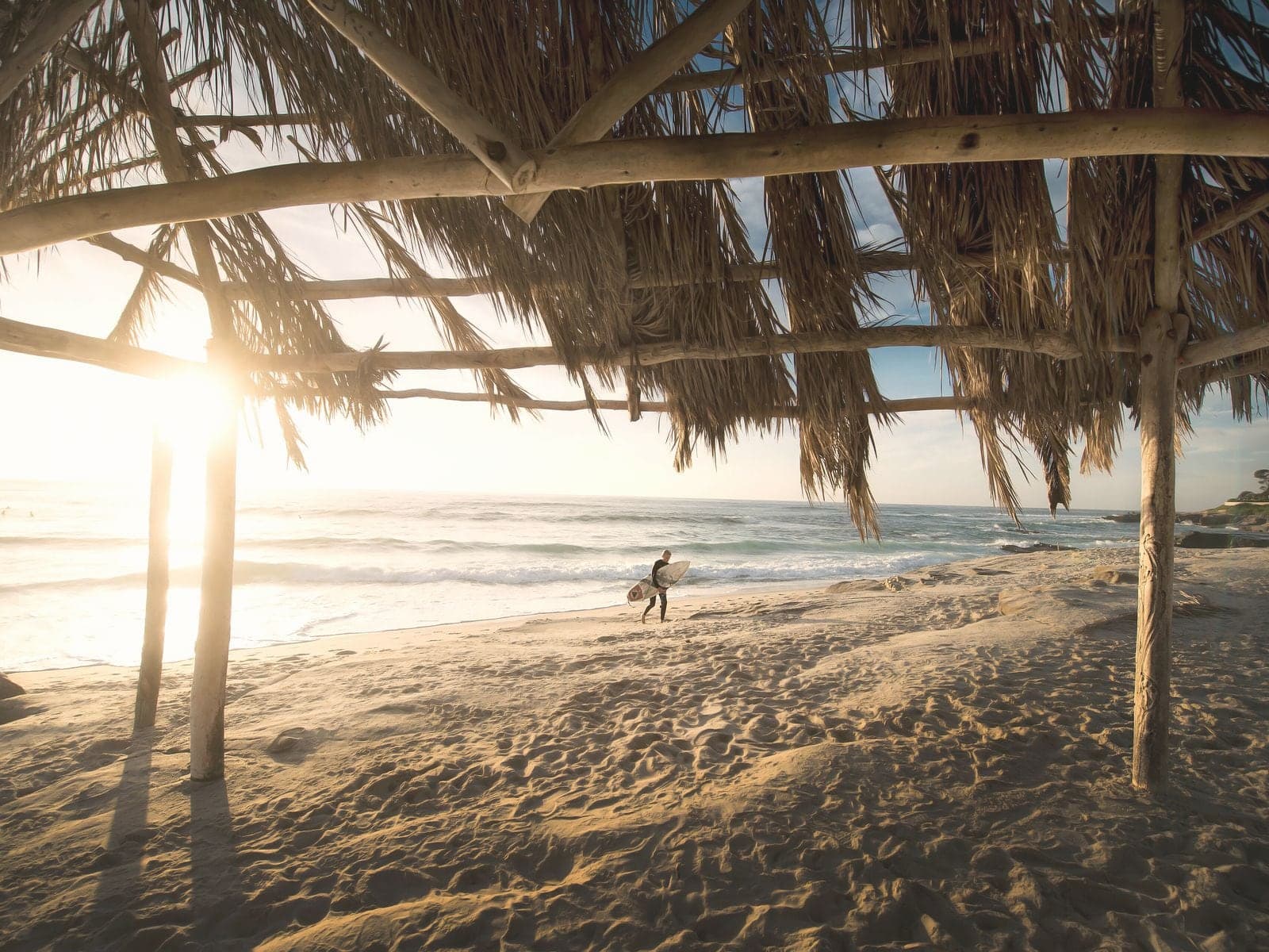 An open thatched palapa on a beach, looking out to the surf.
